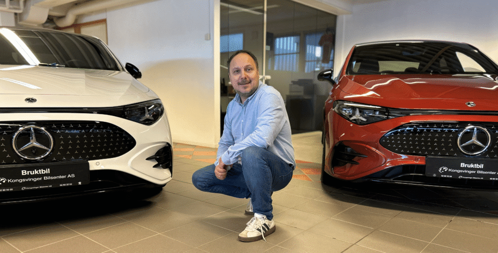 Ansatt hos Kongsvinger Bilsenter sitter på huk mellom to nesten nye Mercedes-Benz CLA i utstillingslokalet.