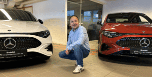 Ansatt hos Kongsvinger Bilsenter sitter på huk mellom to nesten nye Mercedes-Benz CLA i utstillingslokalet.